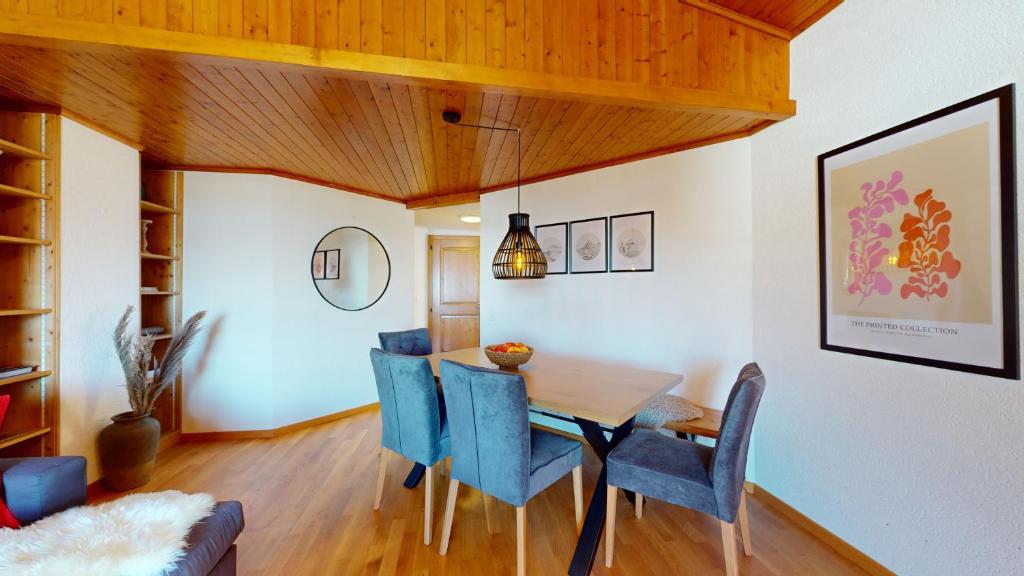 a dining room with a wooden table and blue chairs at No 8 Bed & Bar in Verbier