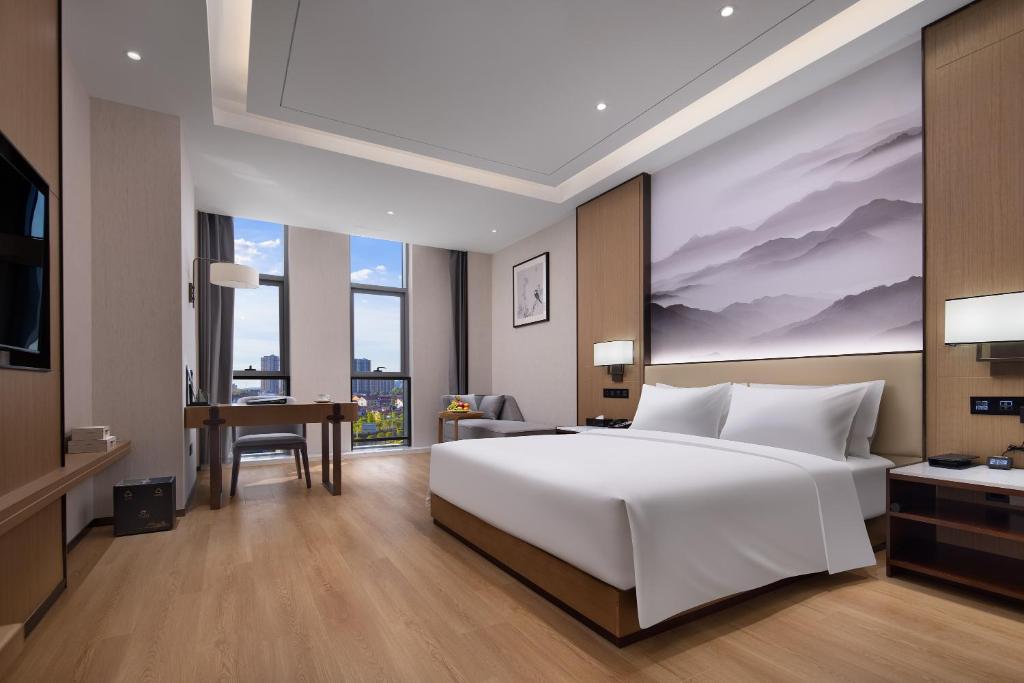 a bedroom with a large white bed and a desk at Metropark Hotel Wuhan in Wuhan