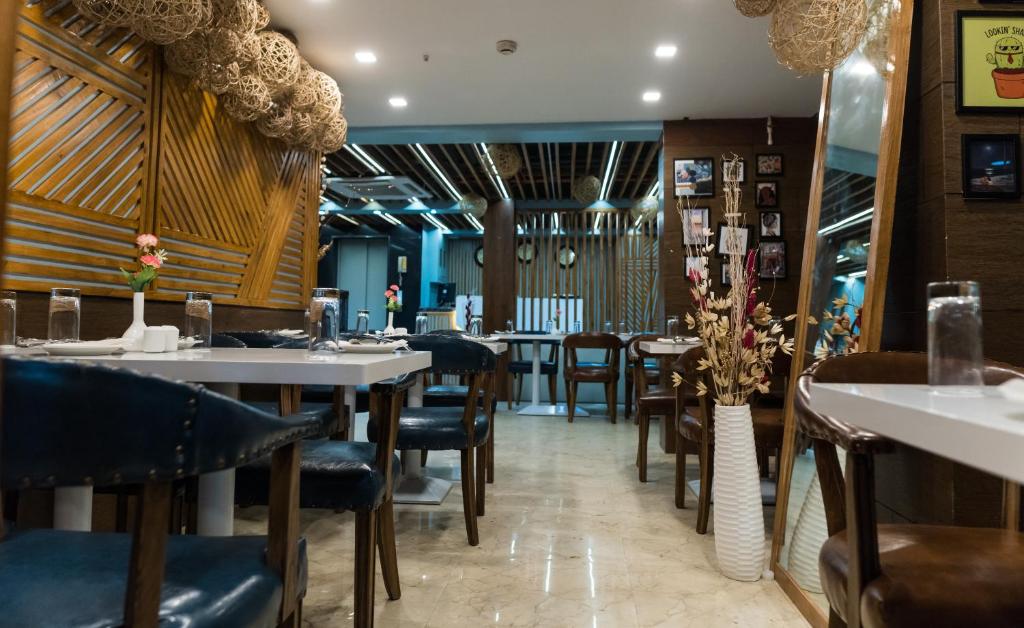 een eetkamer met tafels en stoelen in een restaurant bij The Avenue Hotel Ballygunge in Calcutta