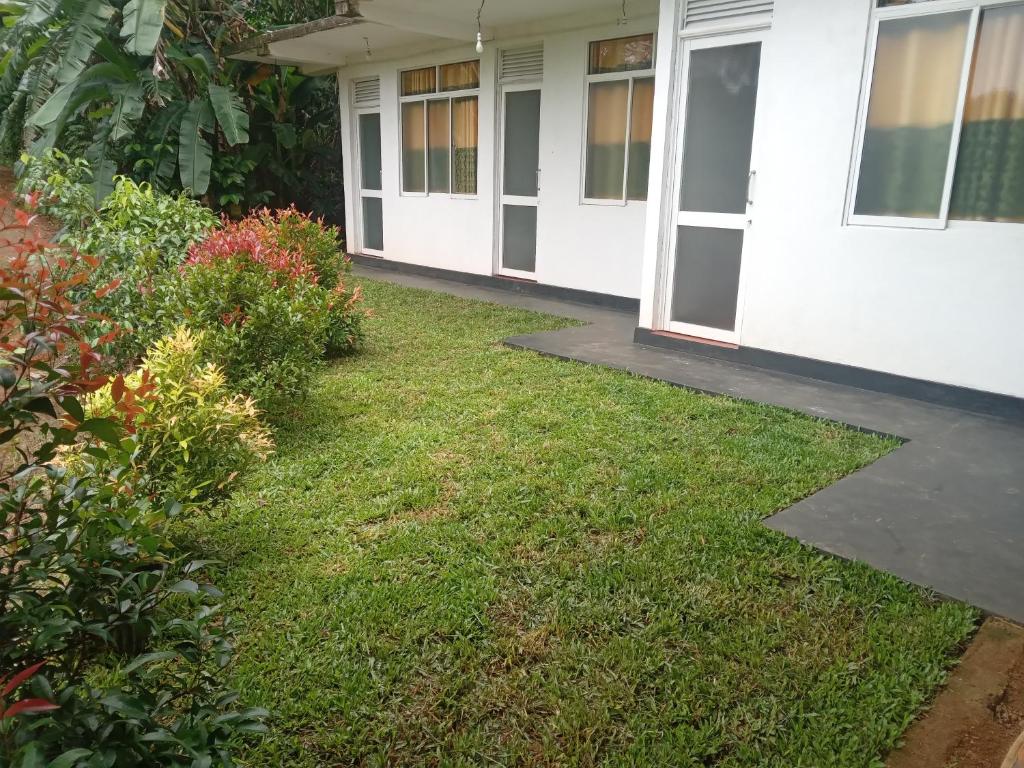 a yard outside of a house with grass and flowers at Rainforest Holiday Inn in Deniyaya