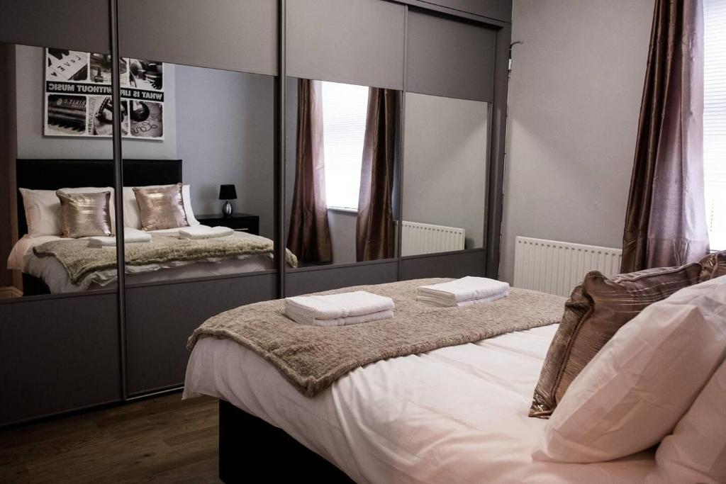 a bedroom with two beds and a large mirror at Inspired Stays- Close to City Centre- 4 Bed House! in Ford Green