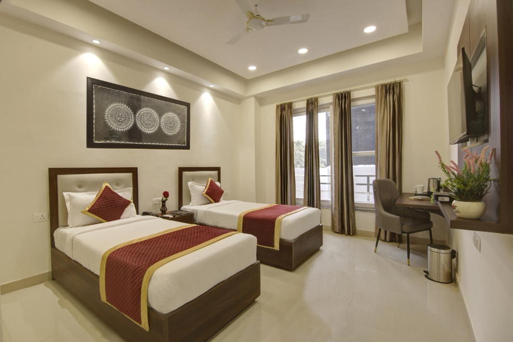 um quarto de hotel com duas camas e uma secretária e uma secretária em Hotel La Mirage em Noida