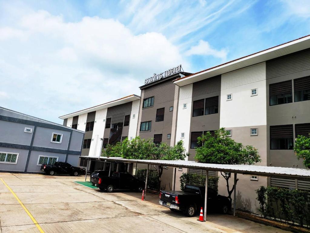 an apartment building with cars parked in a parking lot at Thanaphat place in Buriram