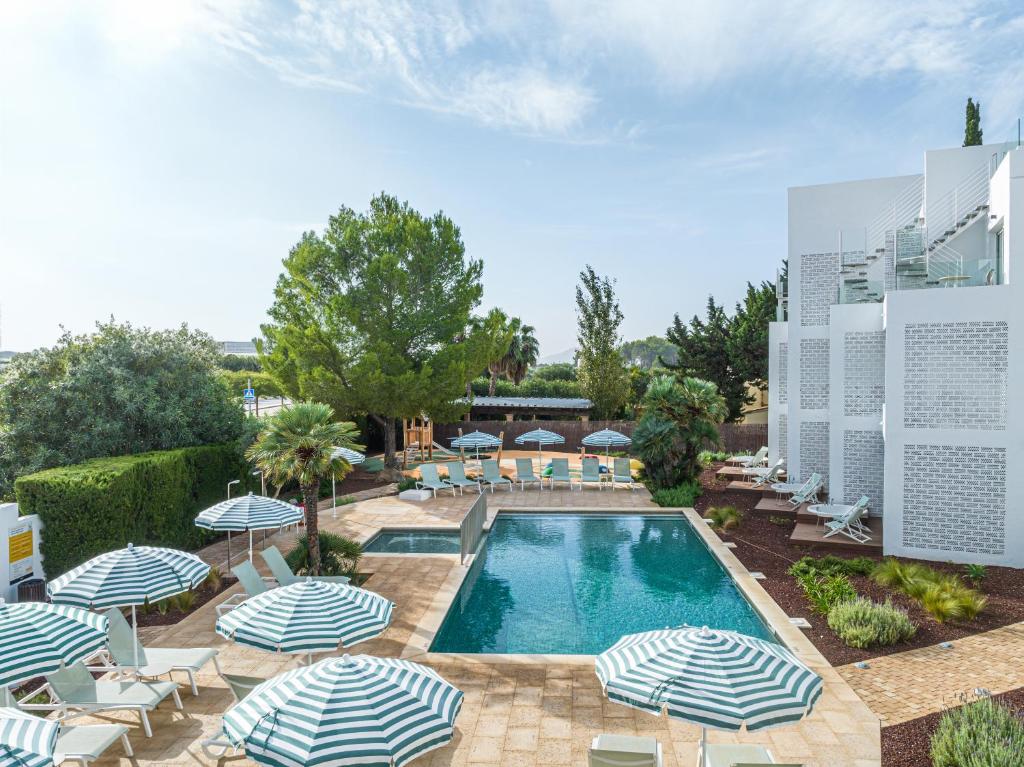 a swimming pool with umbrellas and lounge chairs at Cabot Las Velas Apartments in Port de Pollensa