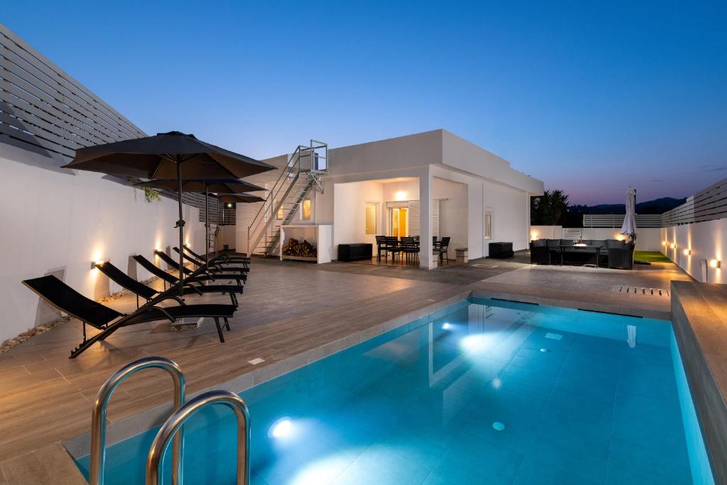 a swimming pool with chairs and an umbrella on a house at Olea Villa in Archipolis