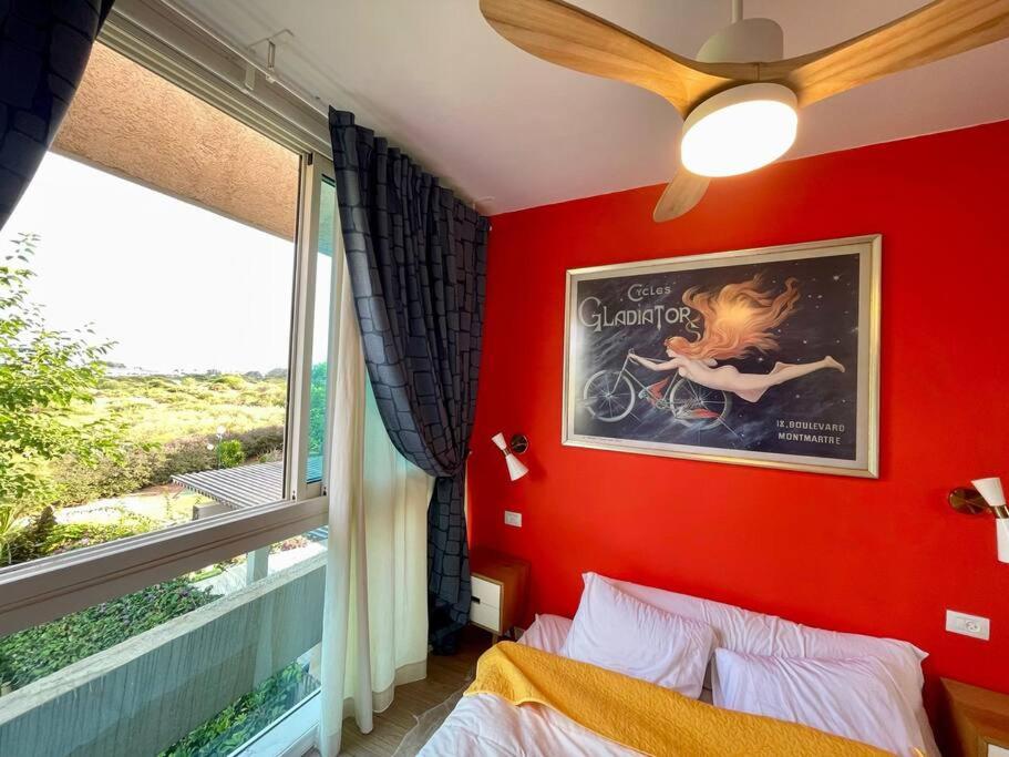 una camera da letto con una parete rossa con un'immagine e un letto di נוף לים 3 חדרים בנאות גולף בקסריה עם בריכה וחדר כושר a Caesarea