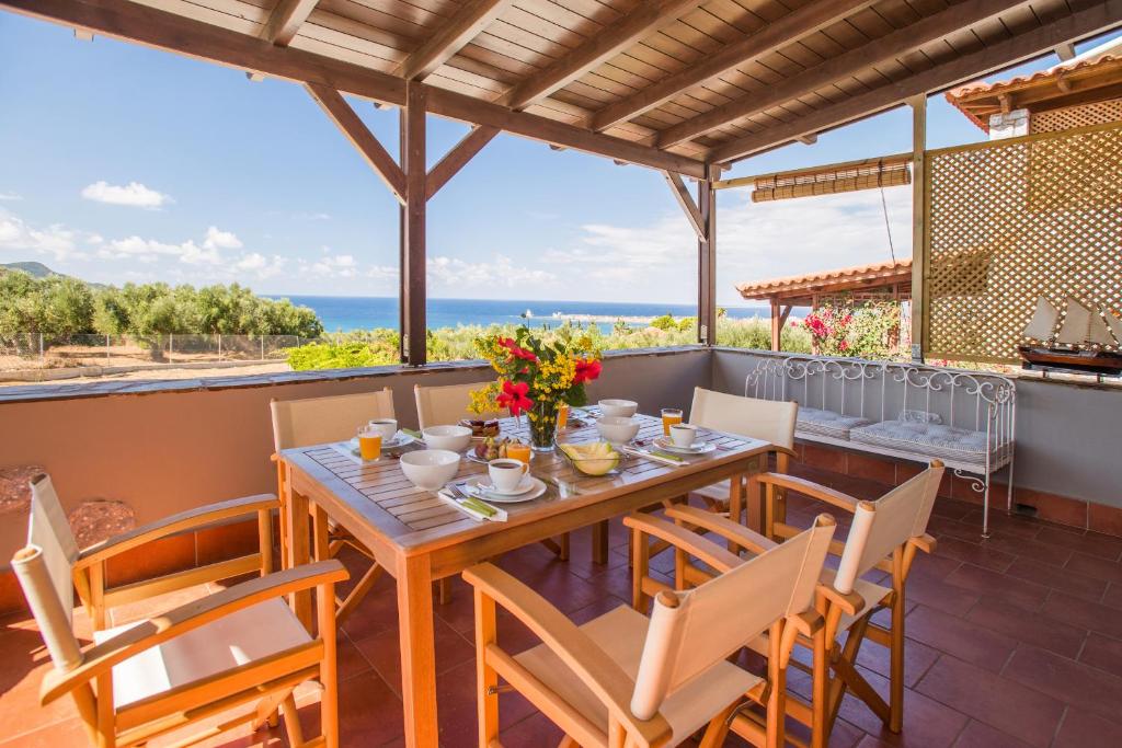 a wooden table and chairs on a patio with a view of the ocean at House of Herbs in Methoni