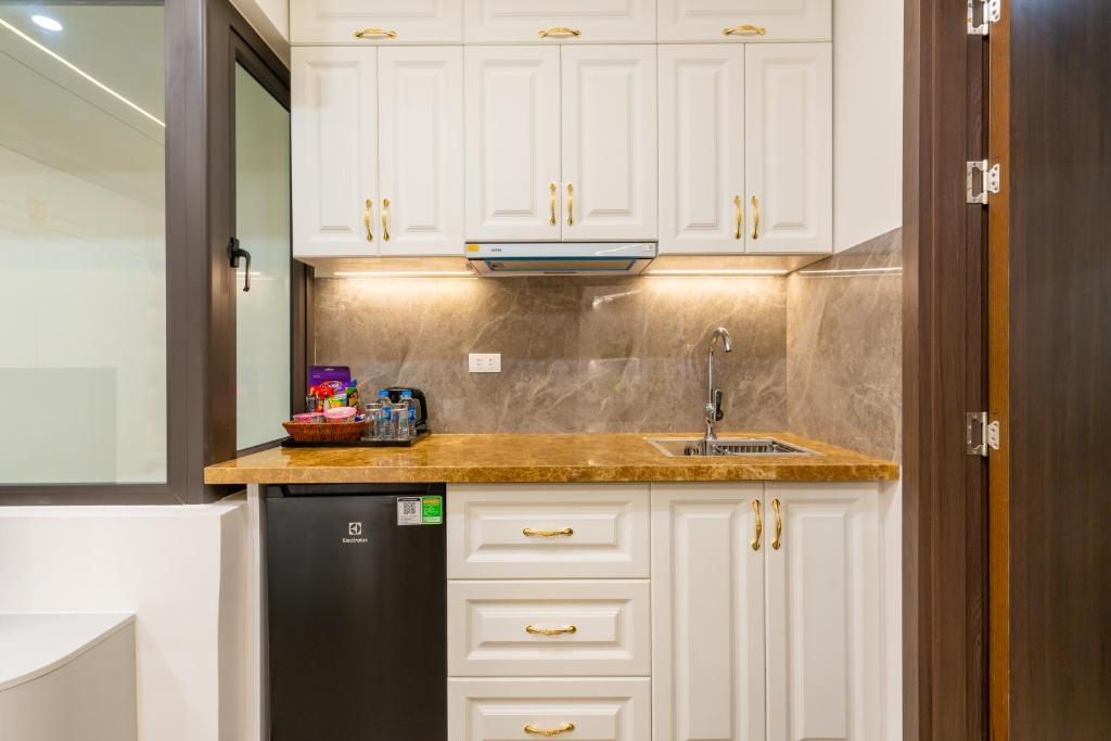 a kitchen with white cabinets and a sink and a refrigerator at CM Hotel & Apartment in Hai Phong