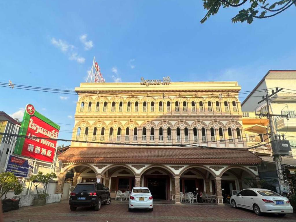 a large yellow building with cars parked in front of it at 万象莉莉酒店 in Vientiane