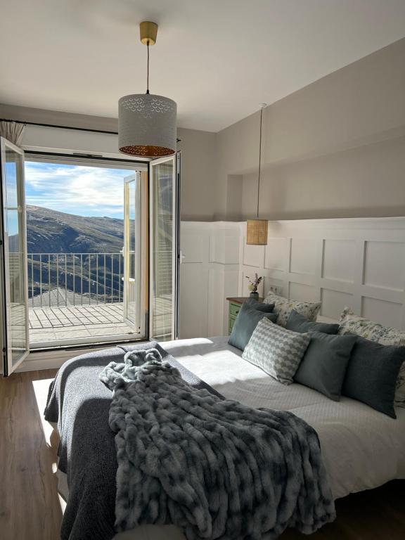 een slaapkamer met een groot bed en een groot raam bij MORAIMA junto a CARD in Sierra Nevada