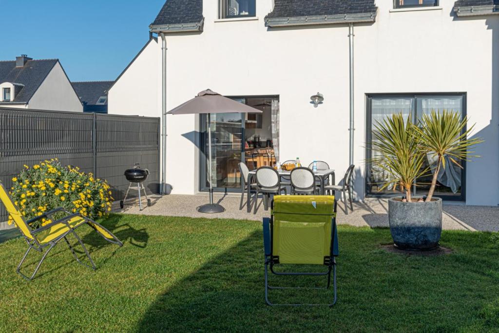 a yard with chairs and tables and a house at Gite de Téno Bras - La Baie in Plouharnel