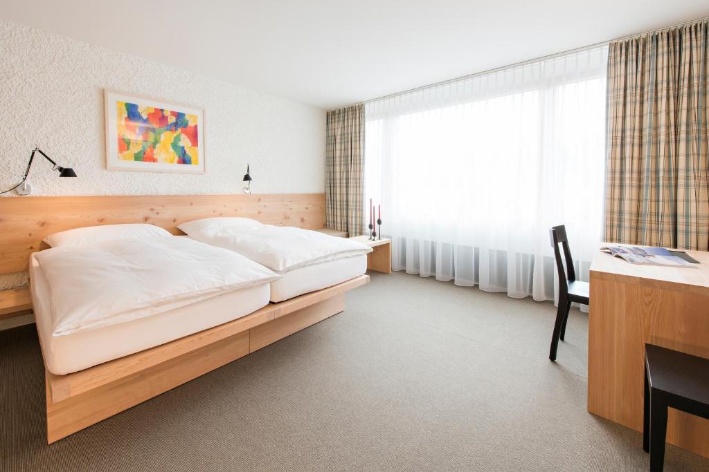 a bedroom with a bed and a desk and a window at Hauser Hotel St. Moritz in St. Moritz