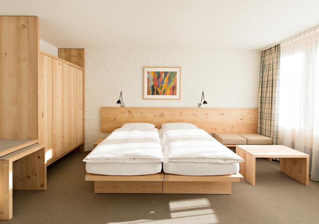 a bedroom with a large bed and a table at Hauser Hotel St. Moritz in St. Moritz