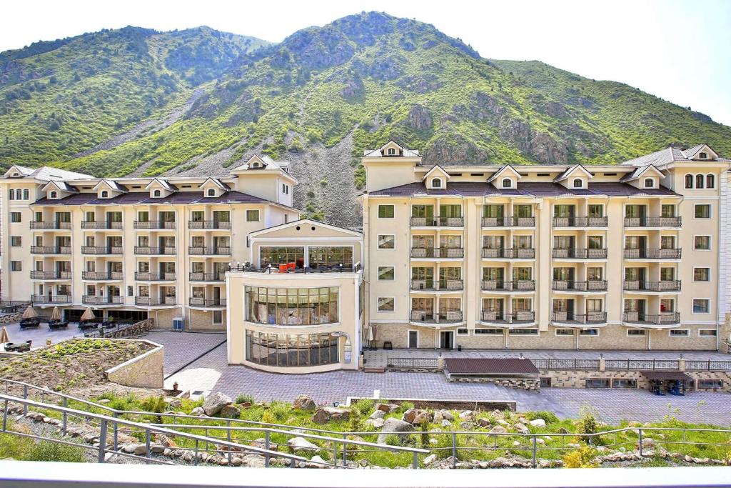 a large building with a mountain in the background at Jannat Resort in Alamedin