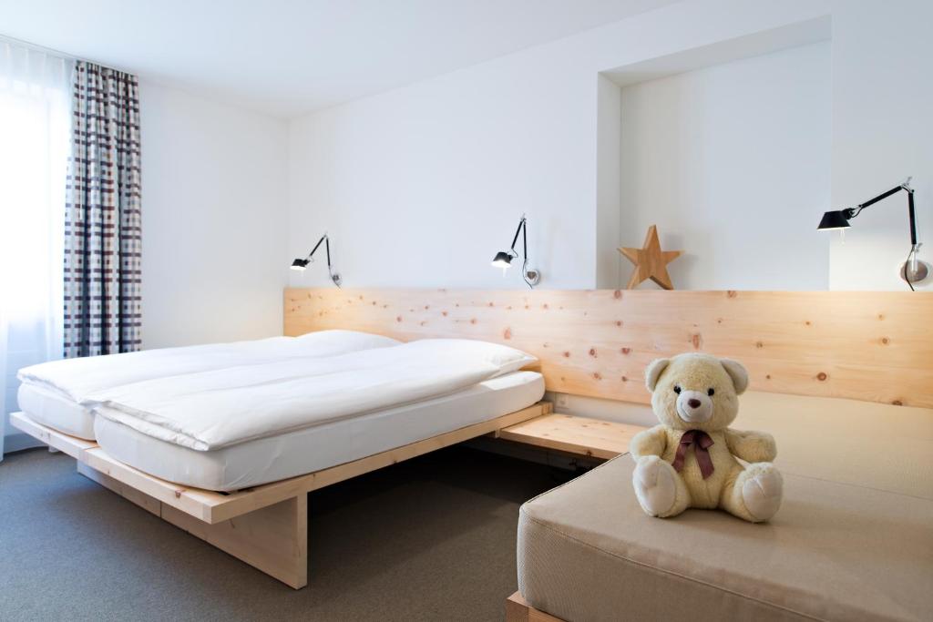 a teddy bear sitting on a bed in a bedroom at Hauser Hotel St. Moritz in St. Moritz