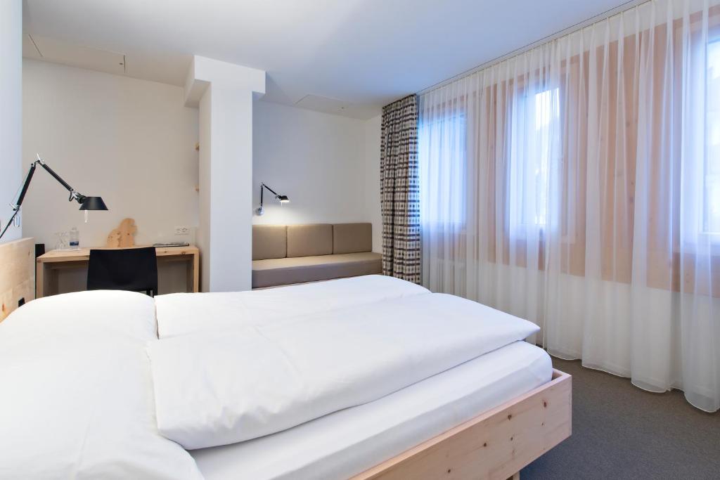 a bedroom with a large white bed and a desk at Hauser Hotel St. Moritz in St. Moritz