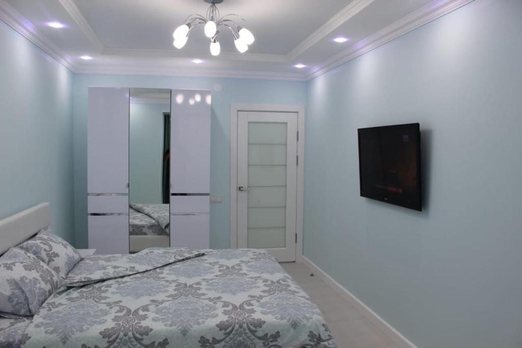 - une chambre avec un lit et une télévision à écran plat dans l'établissement Двухкомнатная квартира в центре города, à Uralsk