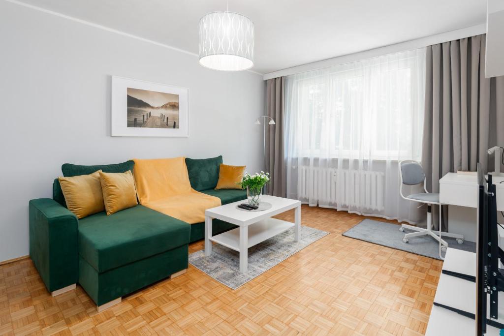 een woonkamer met een groene bank en een tafel bij Apartment Floriana Stablewskiego Poznań by Renters in Poznań