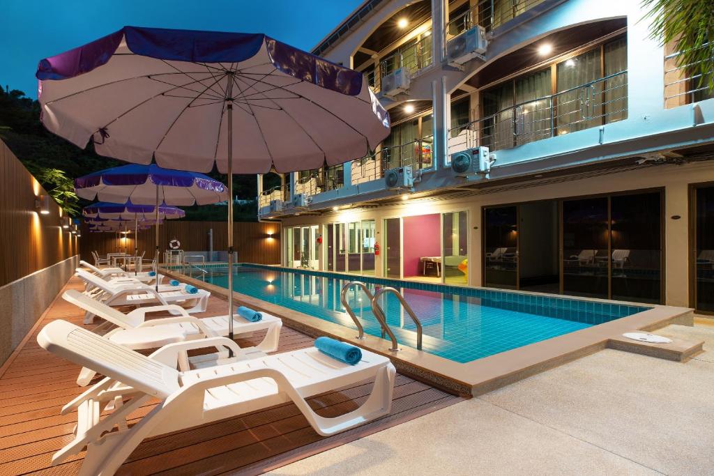 a hotel swimming pool with lounge chairs and an umbrella at Aspira Resort Klong Muang Krabi in Klong Muang Beach