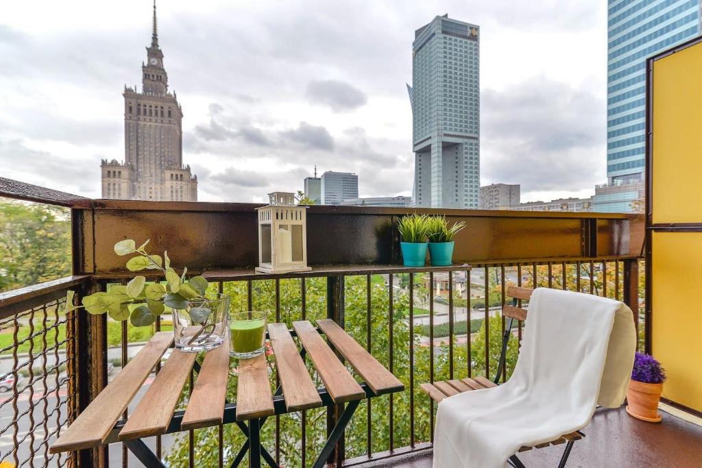 a balcony with a wooden table and a view of the city at Rent like home - Świętokrzyska 32 in Warsaw