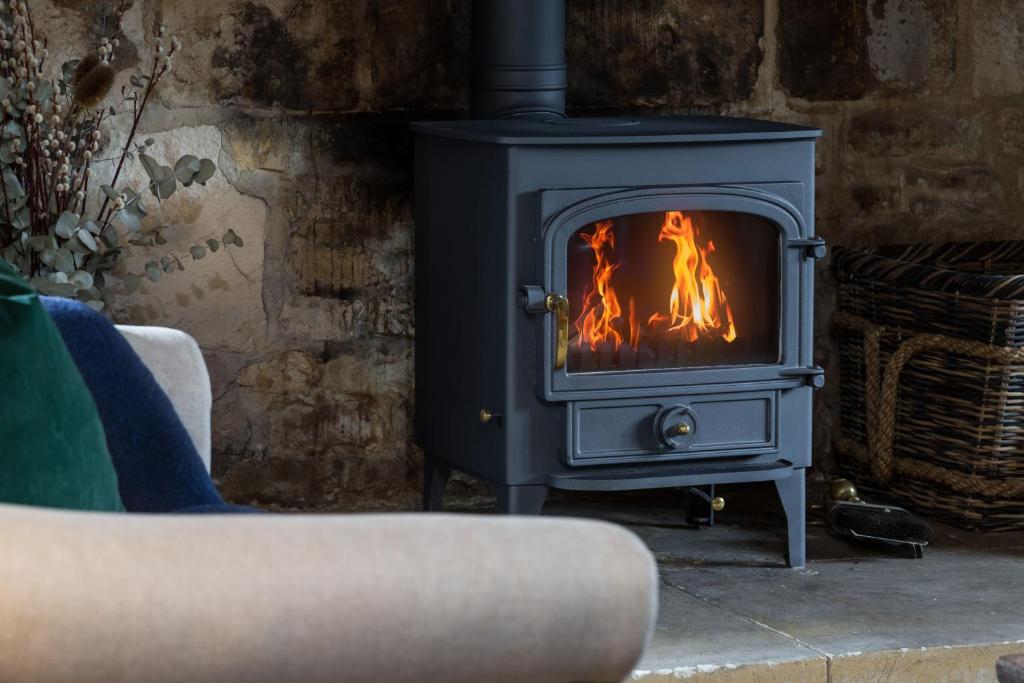 un soggiorno con divano e stufa a legna. di 1 Chestnut Corner a Stanton