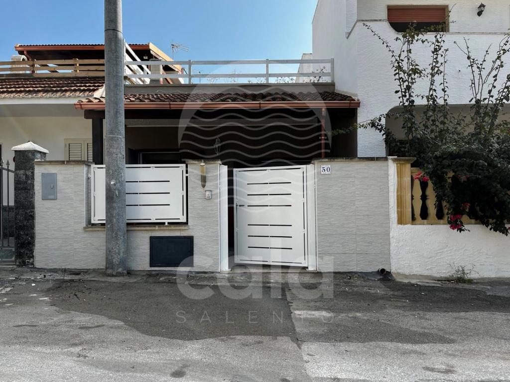ein Haus mit weißen Türen an der Seite in der Unterkunft CASA ROSSELLA in Torre Lapillo