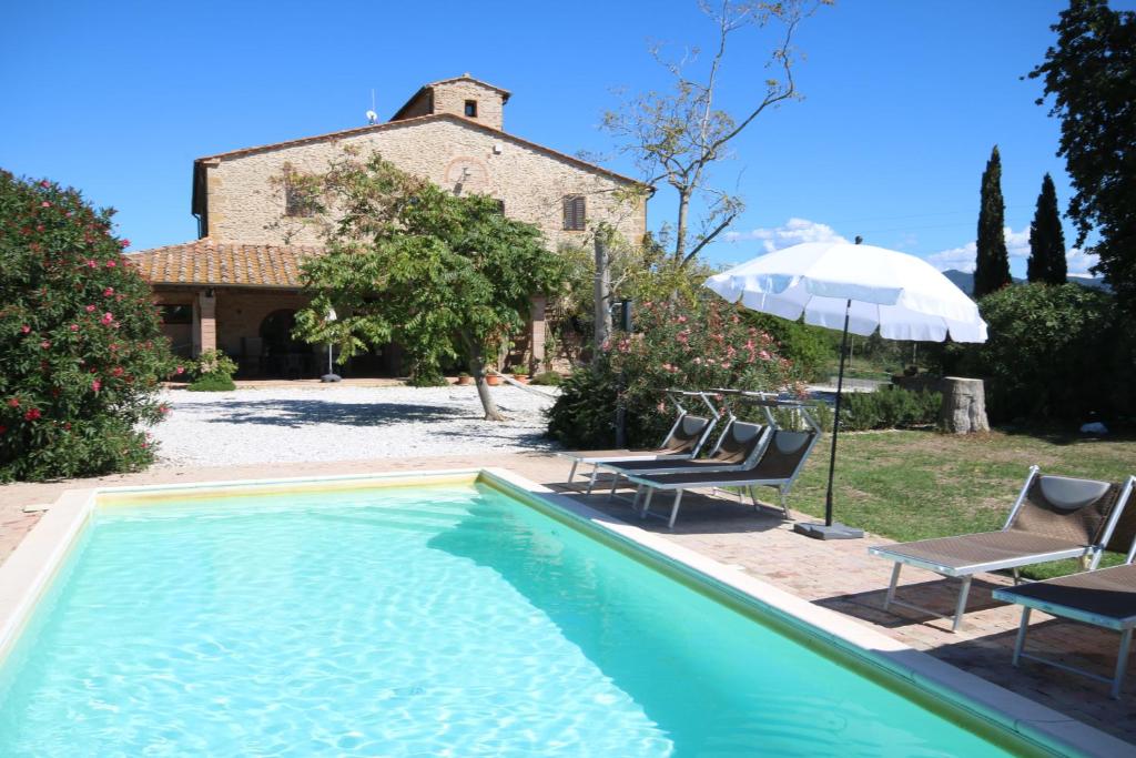 een zwembad voor een huis met 2 stoelen en een parasol bij Podere Campo alle Serpi in Bibbona
