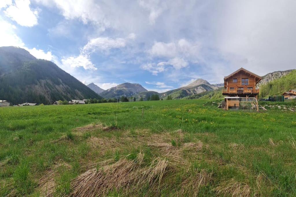 uma casa num campo com montanhas ao fundo em Chalet La Cincia em Arvieux
