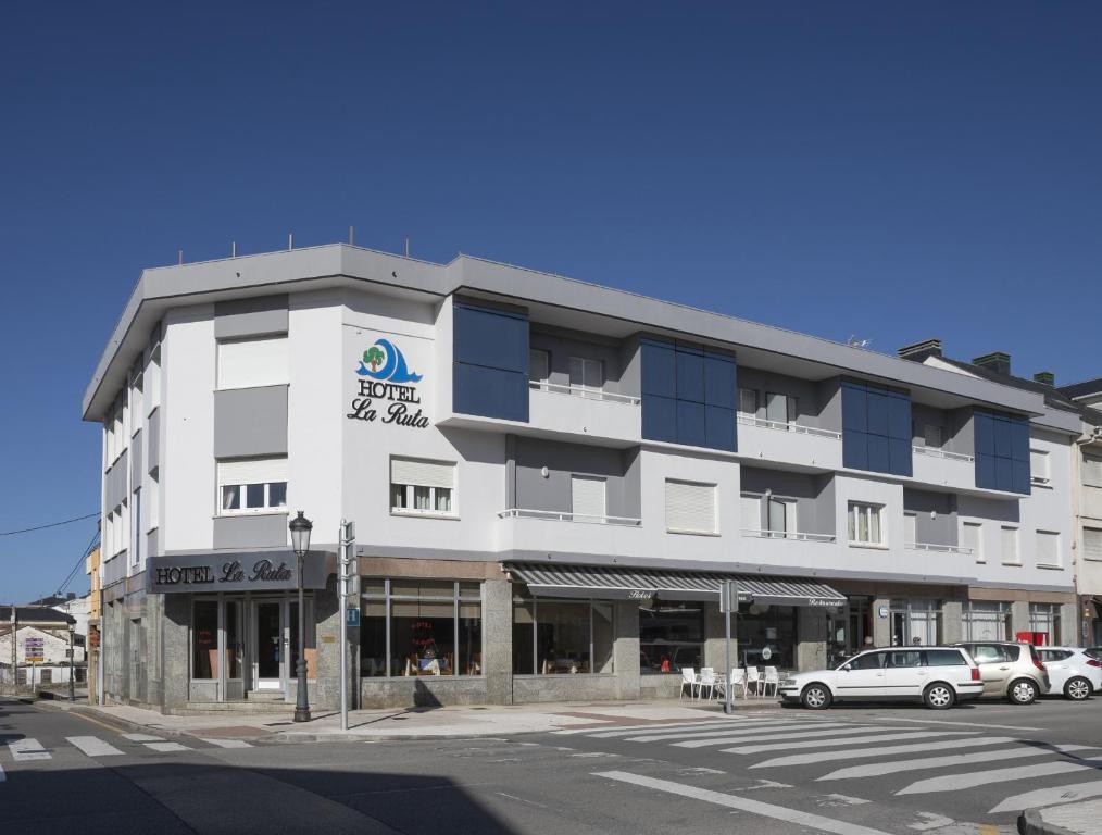 un gran edificio blanco con coches estacionados frente a él en Hotel La Ruta, en Tapia de Casariego