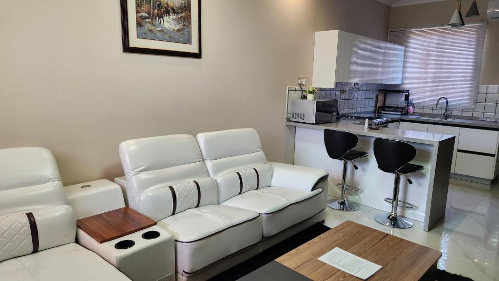 a living room with a white couch and a kitchen at Chez Gabrielle in Lusaka