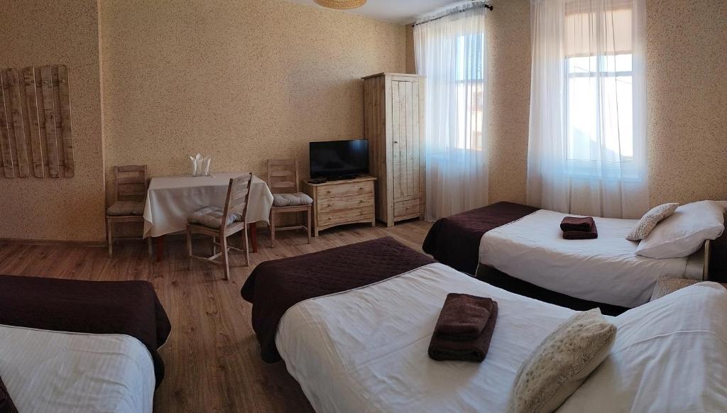 オパレニツァにあるKAMIENICA Pokoje & Restauracjaのベッド3台、テーブル、テレビが備わるホテルルームです。