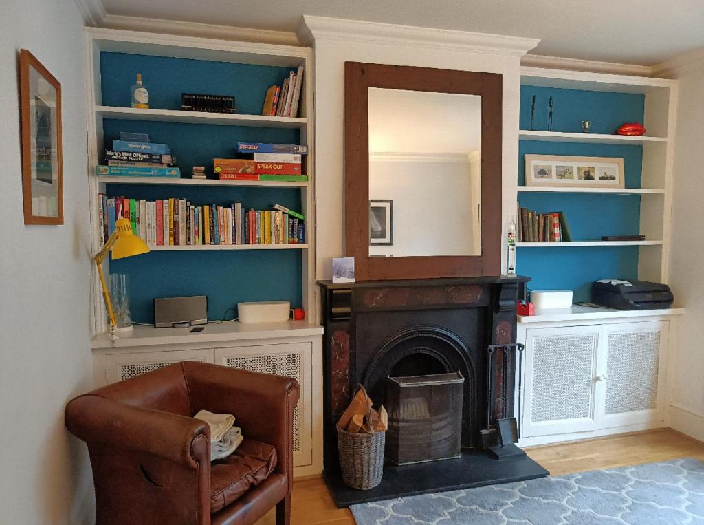 a living room with a fireplace and a chair and a mirror at Victorian Terraced House in Salisbury; 3 bedrooms in Salisbury