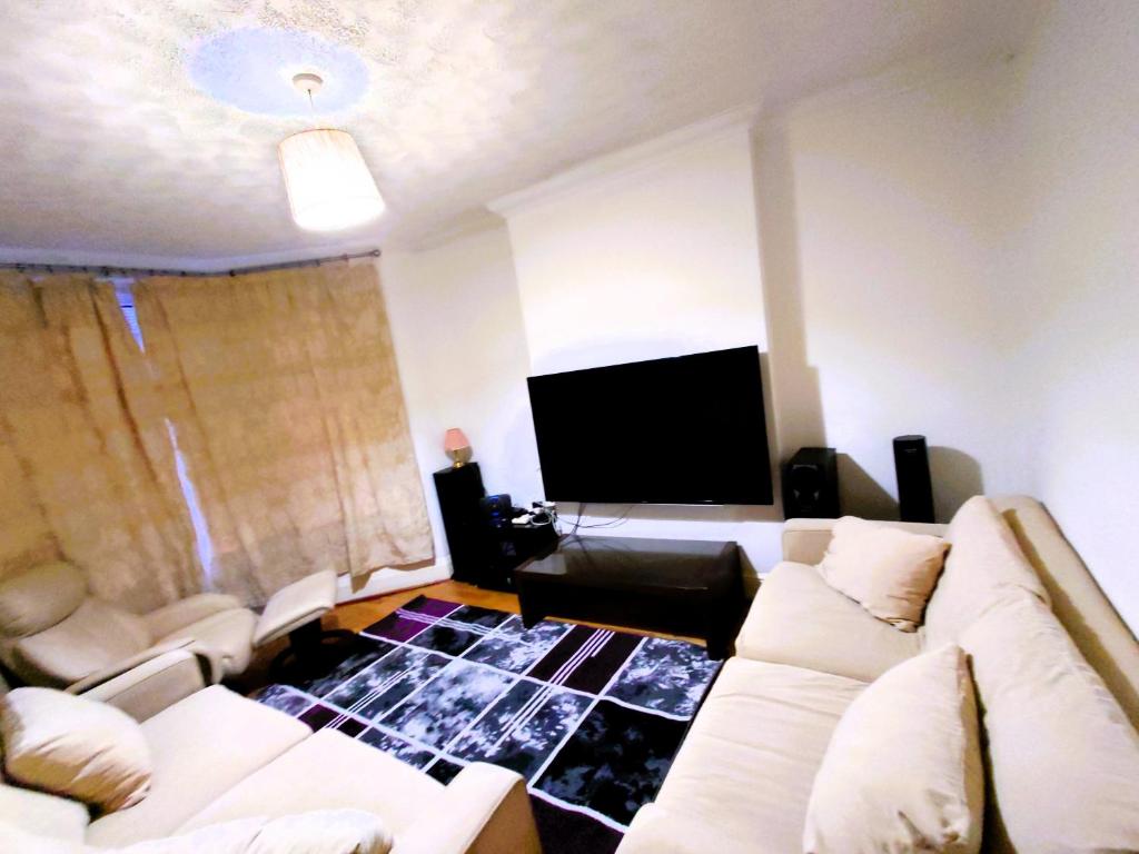 sala de estar con sofás blancos y TV de pantalla plana en Edwardian 5 bedroom townhouse, next to underground, en Londres