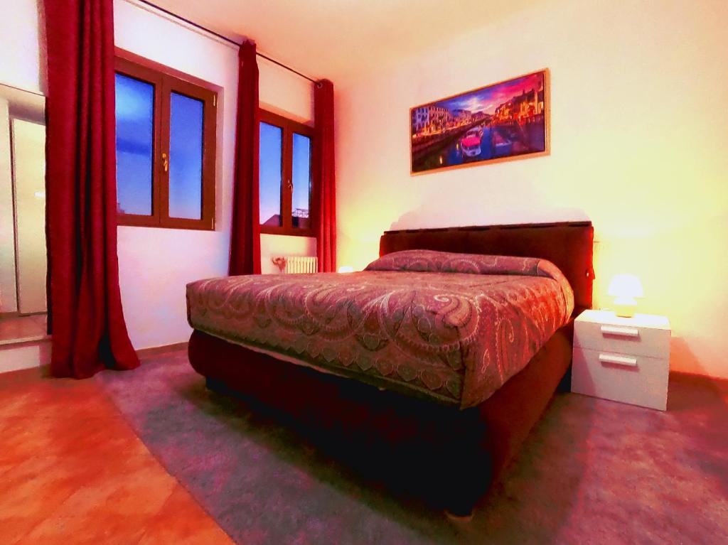 L' appartamento sul Naviglio في ميلانو: غرفة نوم مع سرير في غرفة مع نوافذ