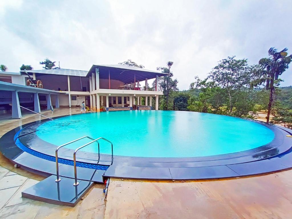 a large swimming pool in front of a house at STAYMAKER Sereno Resort in Sakleshpur