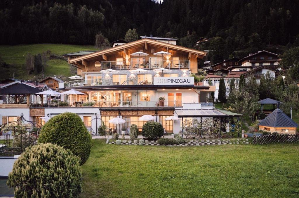 un gran edificio en una colina con un campo de césped en Hotel Garni Pinzgau, Bernd Hüttl, en Neukirchen am Großvenediger