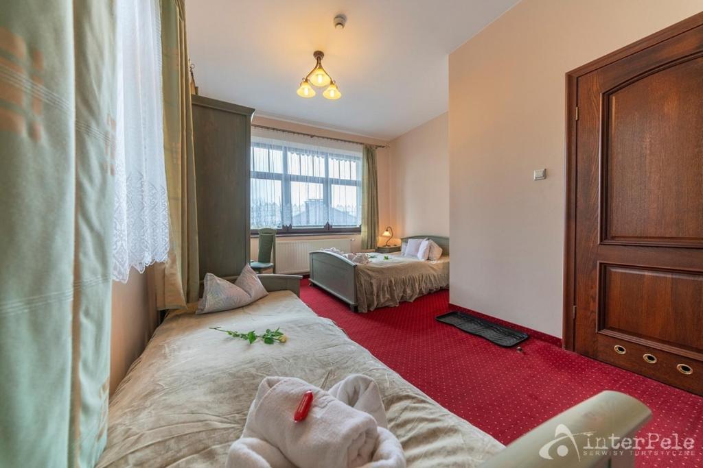 Bright twin room with beds, window light, towels and single rose on bed.