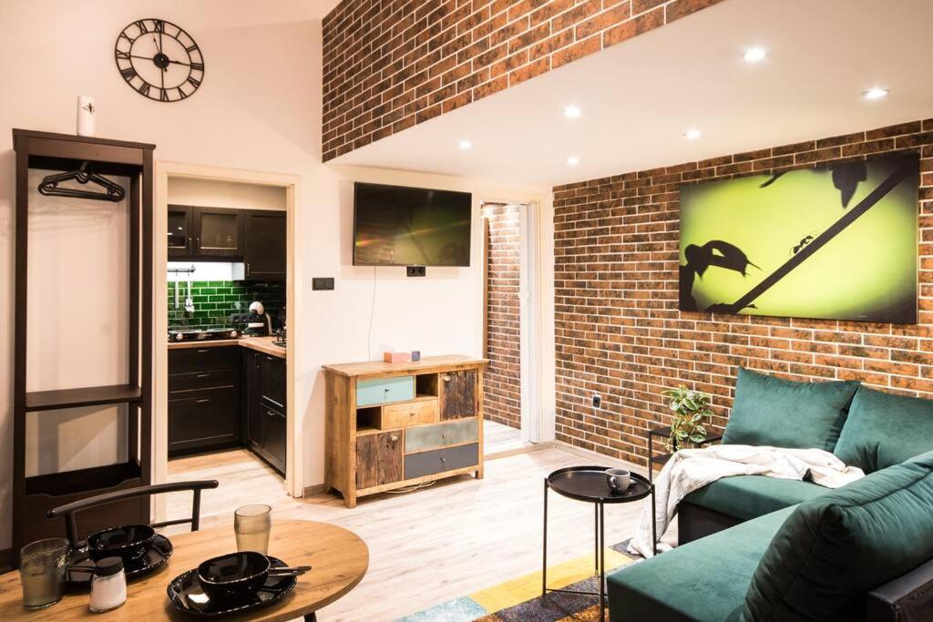 ein Wohnzimmer mit einem grünen Sofa und einer Ziegelwand in der Unterkunft Budapest Boulvard Green in Budapest