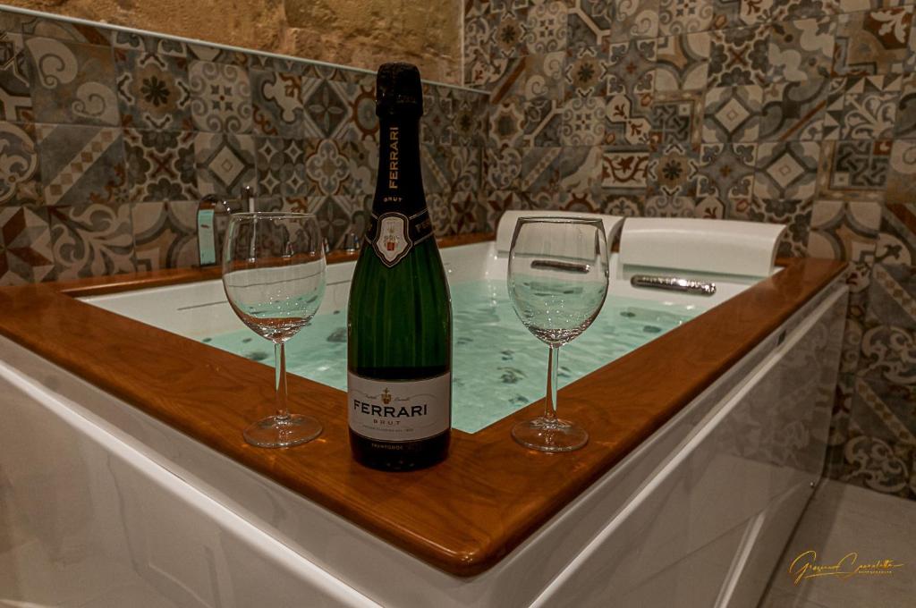 - Uma garrafa de champanhe e 2 copos na banheira; em Victoria Luxury Suite em Lizzanello