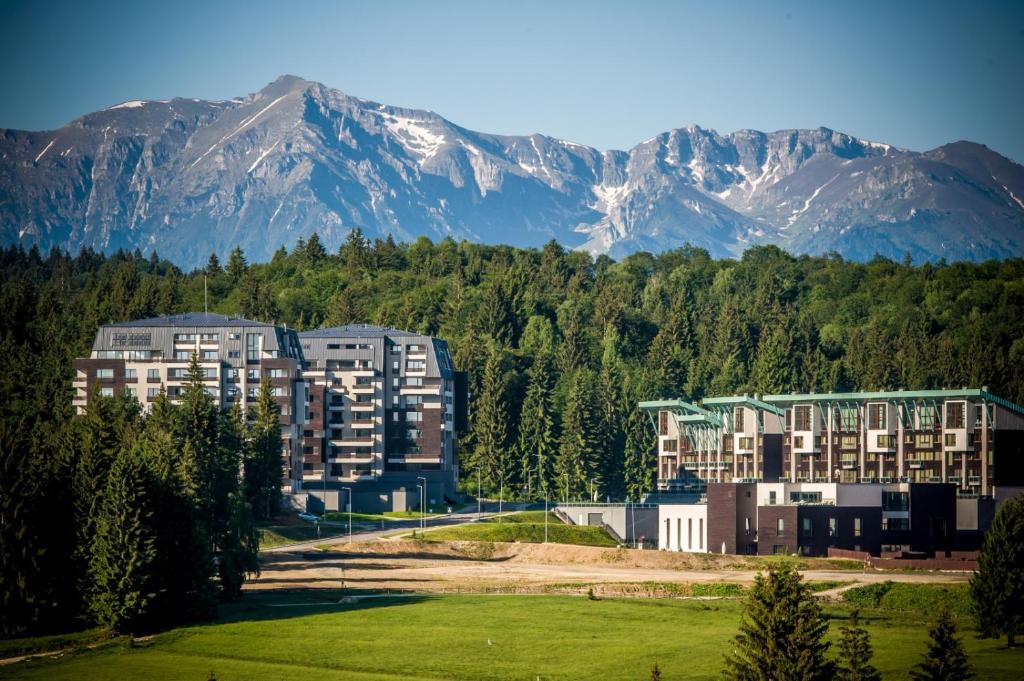 a largeartment building with mountains in the background at Pine Woods Apartment A43 in Silver Mountain in Poiana Brasov