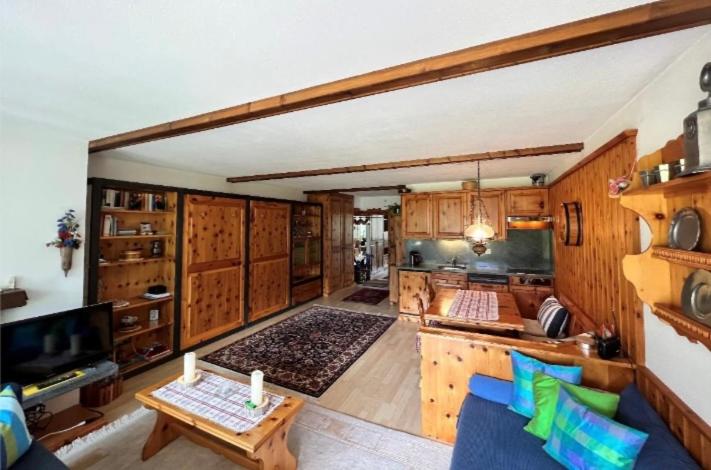 a large kitchen with wooden cabinets and a living room at Alpine Cocoon in Churwalden
