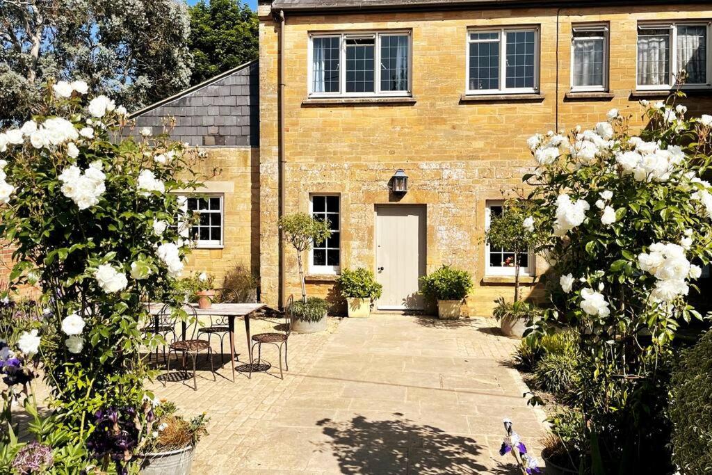 a brick building with a table and white roses at Escape to Ash House 18th Century Manor in Somerset in Martock