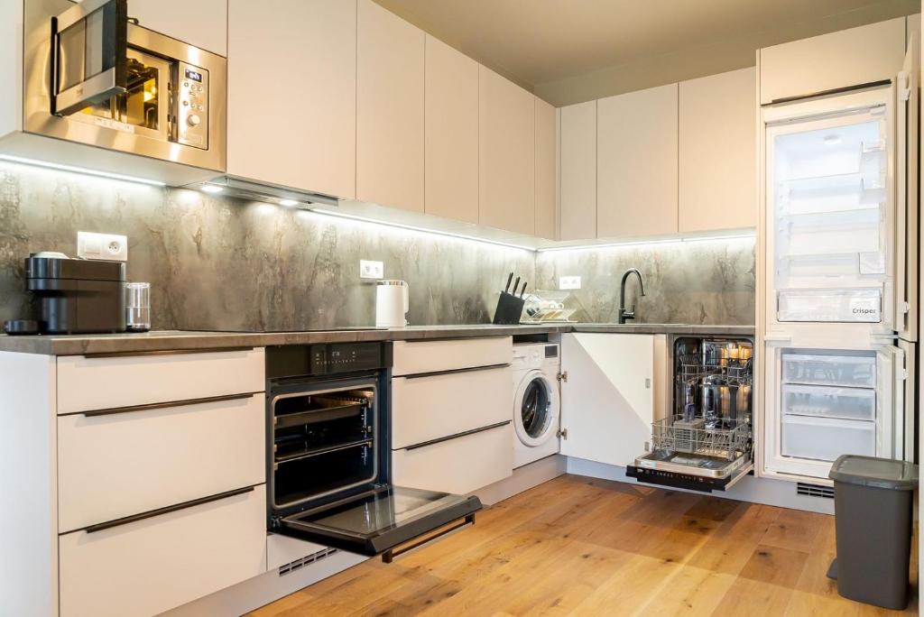 a kitchen with white cabinets and a washer and dryer at Trio Harrachov in Harrachov
