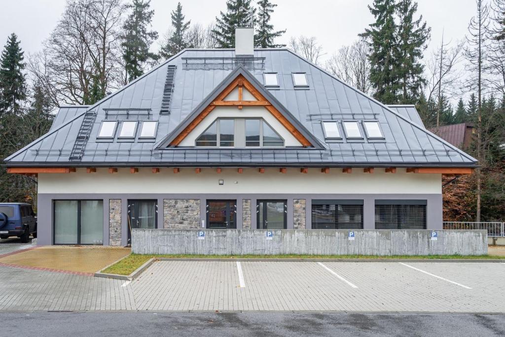 a house with a gambrel roof with a parking lot at Trio Harrachov in Harrachov