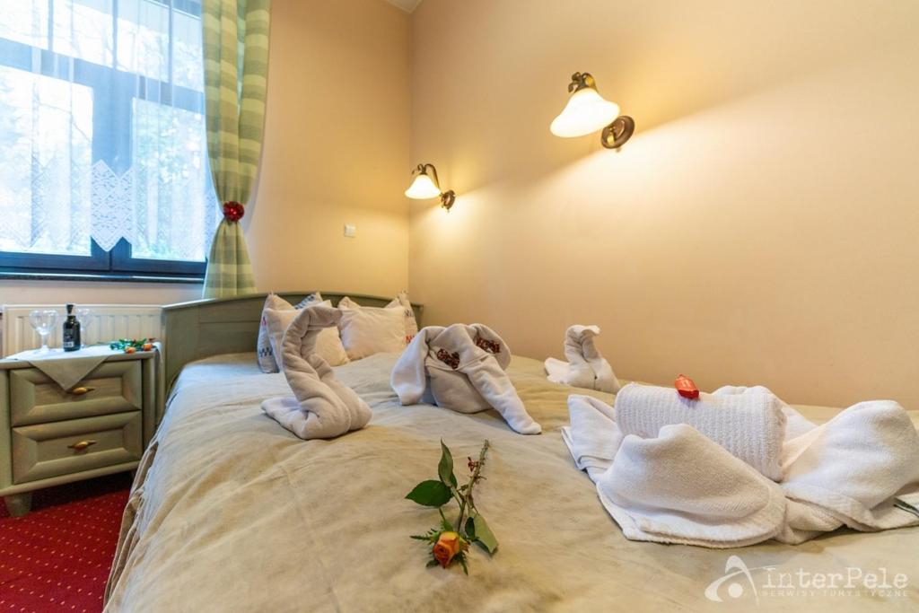 Cozy double bed with towel swans, single rose on duvet, bedside window and warm lamps.