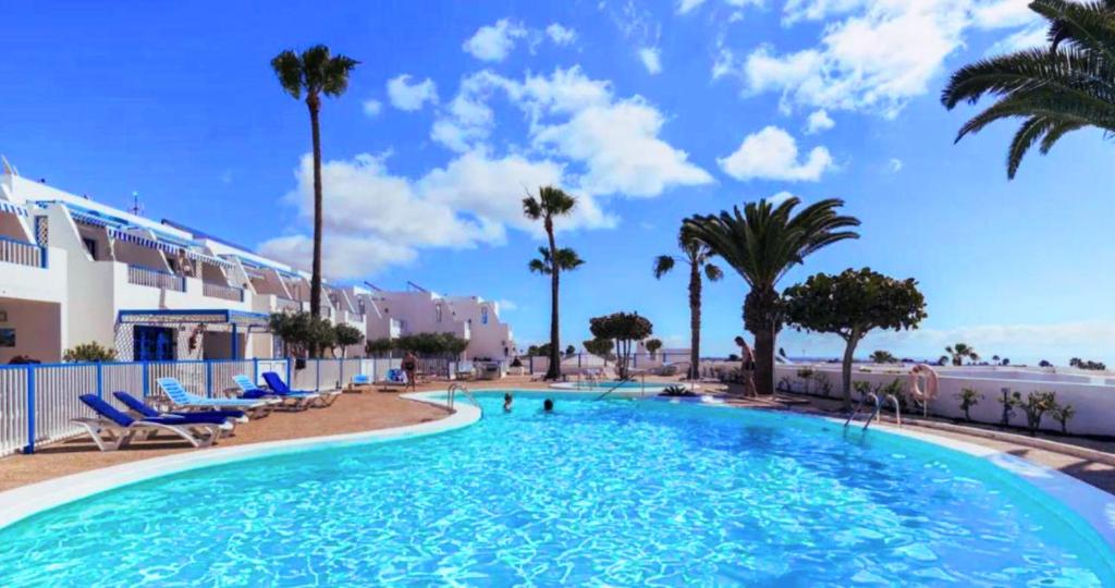 a large swimming pool with palm trees in a resort at Ocean & Pool view Puerto del Carmen in Puerto del Carmen