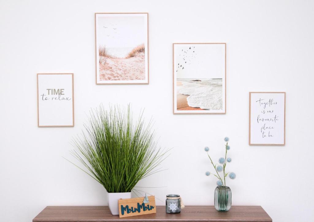 a shelf with four pictures on a wall with a plant at FeWo Varis in Röbel