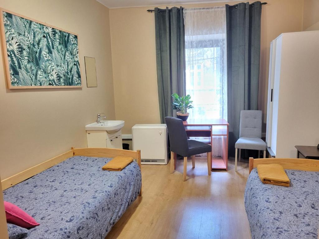 1 Schlafzimmer mit 2 Betten, einem Tisch und einem Schreibtisch in der Unterkunft Hostel Gliwice Centrum in Gliwice