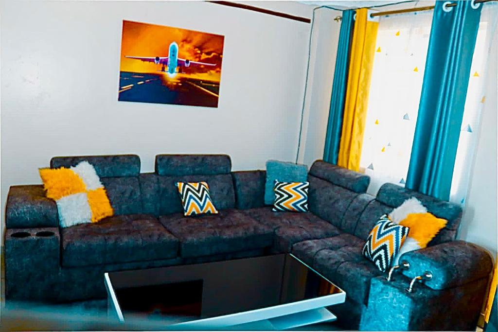 a living room with a blue couch with pillows at Tashma Airbnb Apartment in Nairobi