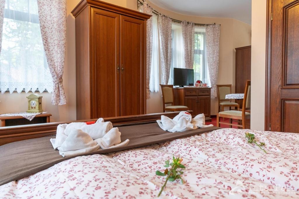 Charming double room featuring floral duvet, towel swans on bed, wooden furniture and TV.